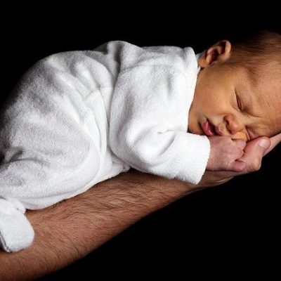 Bébé venant de naître qui dort paisiblment sur le bras de son papa
